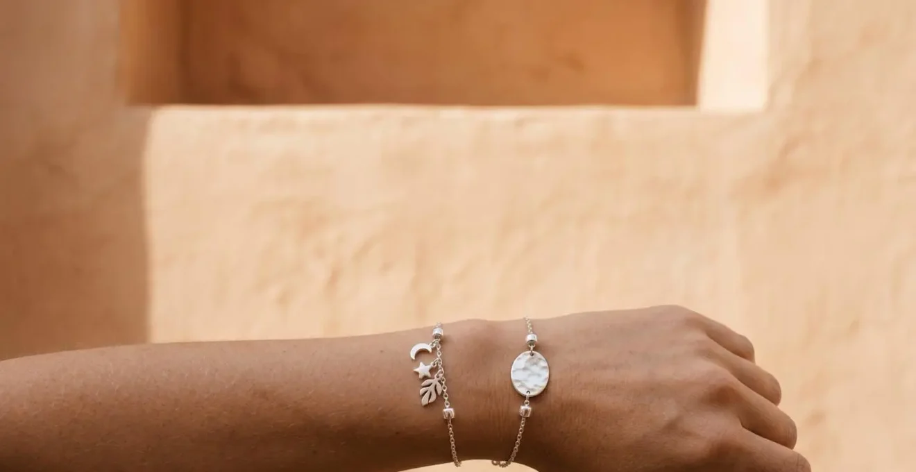 Composición visual de charms de distintos tamaños agrupados asimétricamente en pulsera de plata mostrando equilibrio y armonía